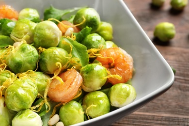 Bowl of delicious salad with Brussels sprouts and shrimps on table, closeup