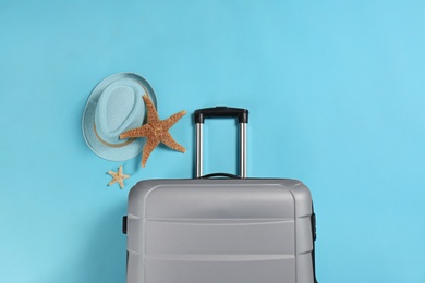 Photo of Stylish suitcase, sea stars and hat on color background, top view