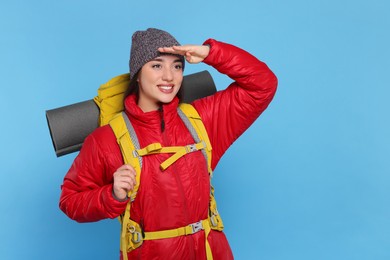 Photo of Smiling young woman with backpack on light blue background, space for text. Active tourism