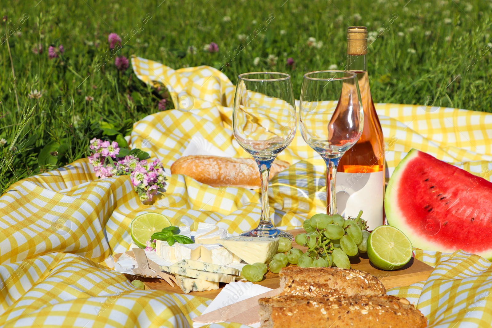 Photo of Picnic blanket with delicious food and wine on green grass outdoors