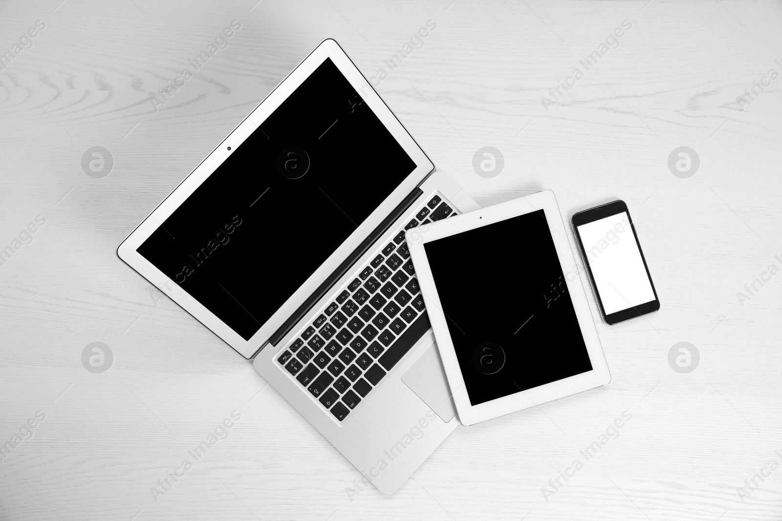 Photo of Devices with blank screens on white wooden background, top view. Mock up for design