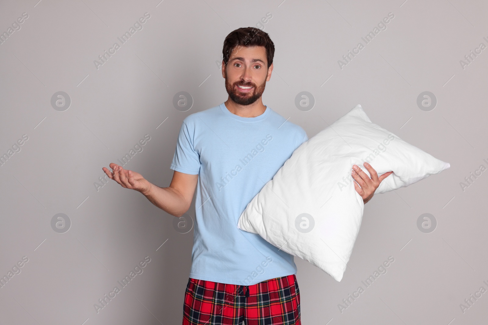 Photo of Emotional handsome man with pillow on light grey background