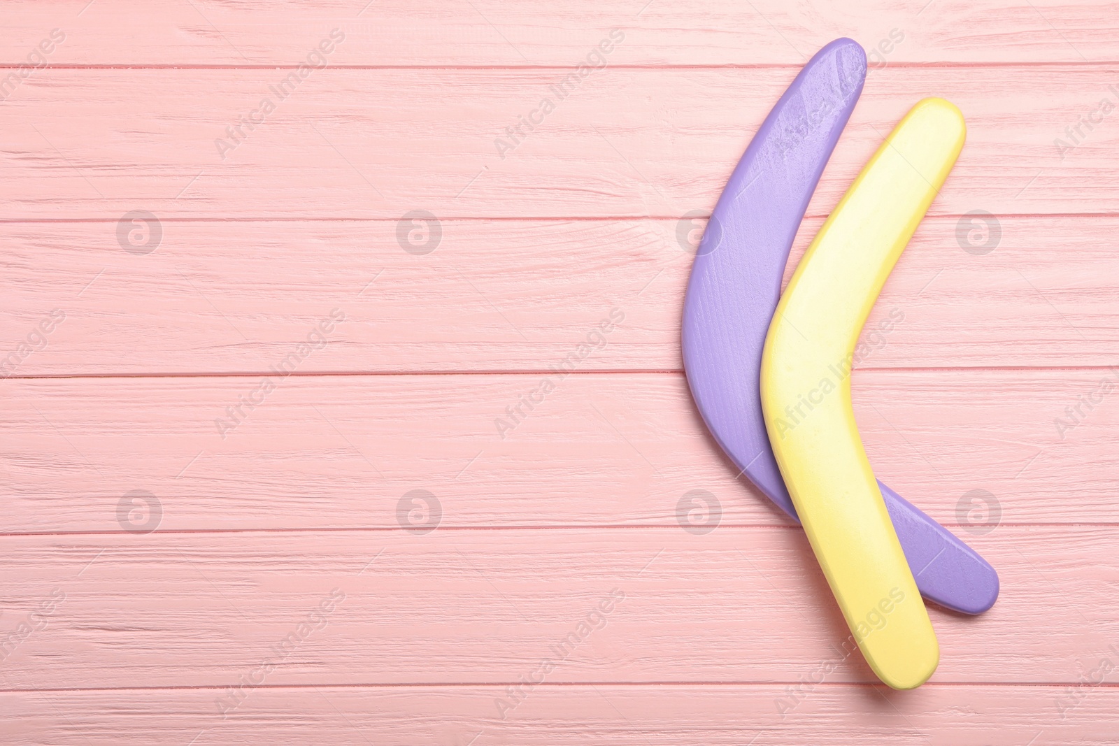 Photo of Boomerangs on pink wooden background, flat lay. Space for text