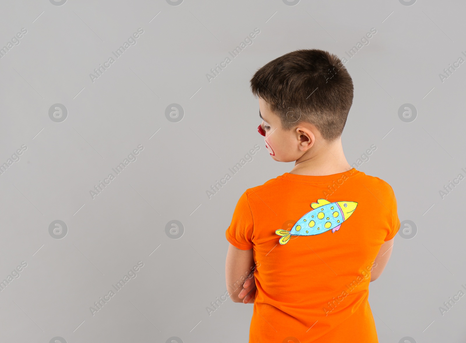 Photo of Preteen boy with paper fish on back against light grey background, space for text. April fool's day