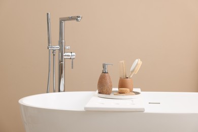 Different personal care products and accessories on bath tub in bathroom