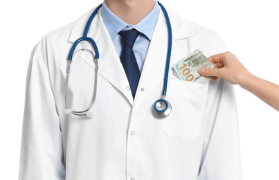 Photo of Patient putting bribe into doctor's pocket on white background, closeup. Corruption in medicine