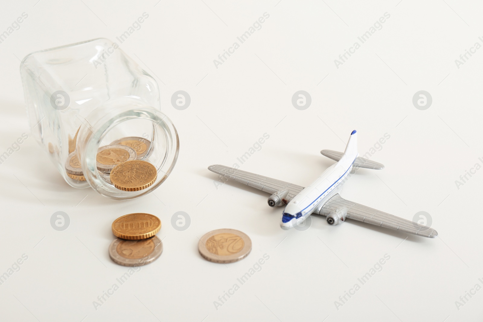 Photo of Toy plane, jar and coins on white background. Travel insurance