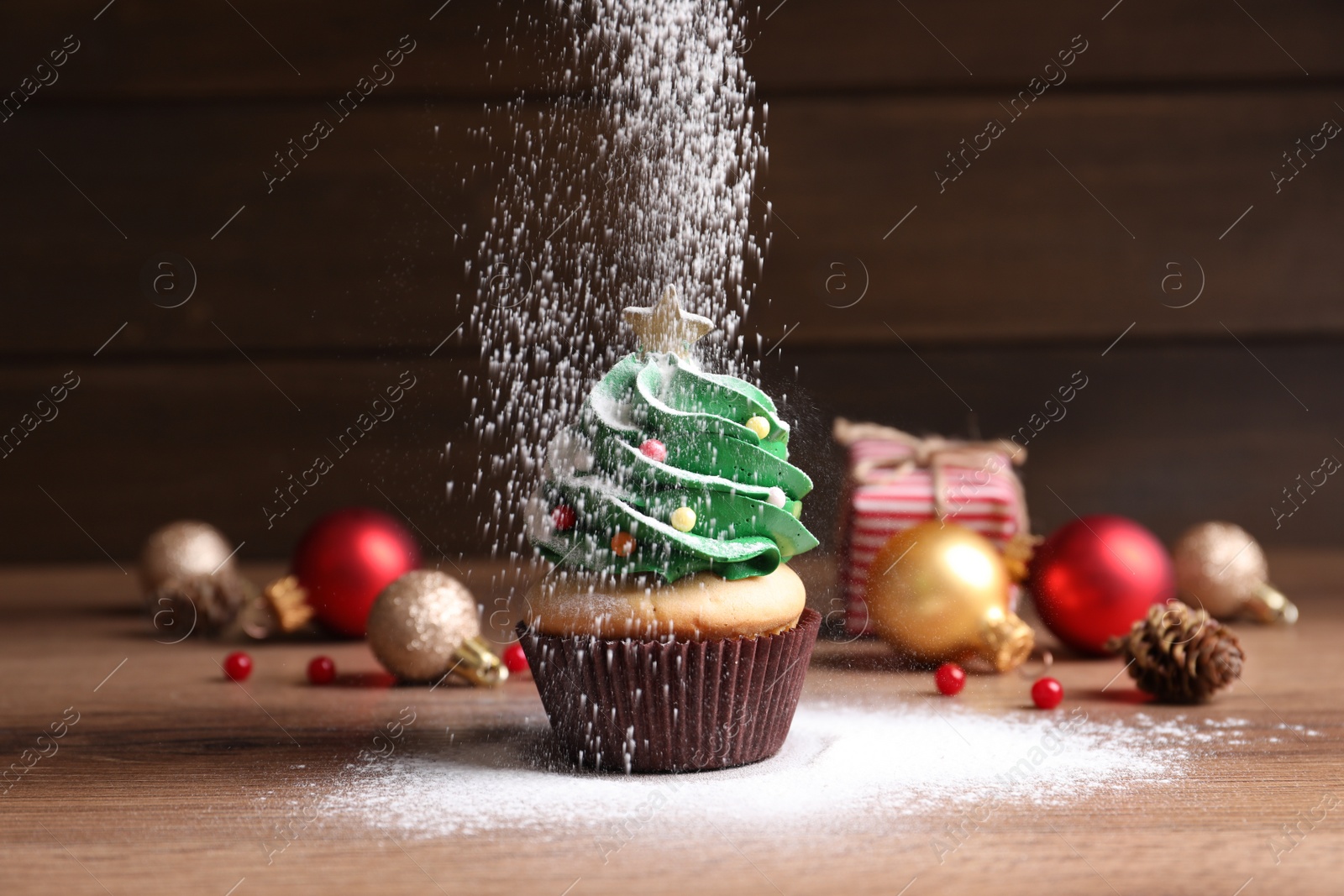 Photo of Sprinkling powdered sugar on Christmas tree shaped cupcake