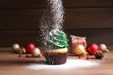 Sprinkling powdered sugar on Christmas tree shaped cupcake