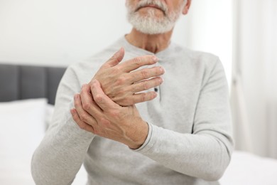 Arthritis symptoms. Man suffering from pain in wrist at home, closeup