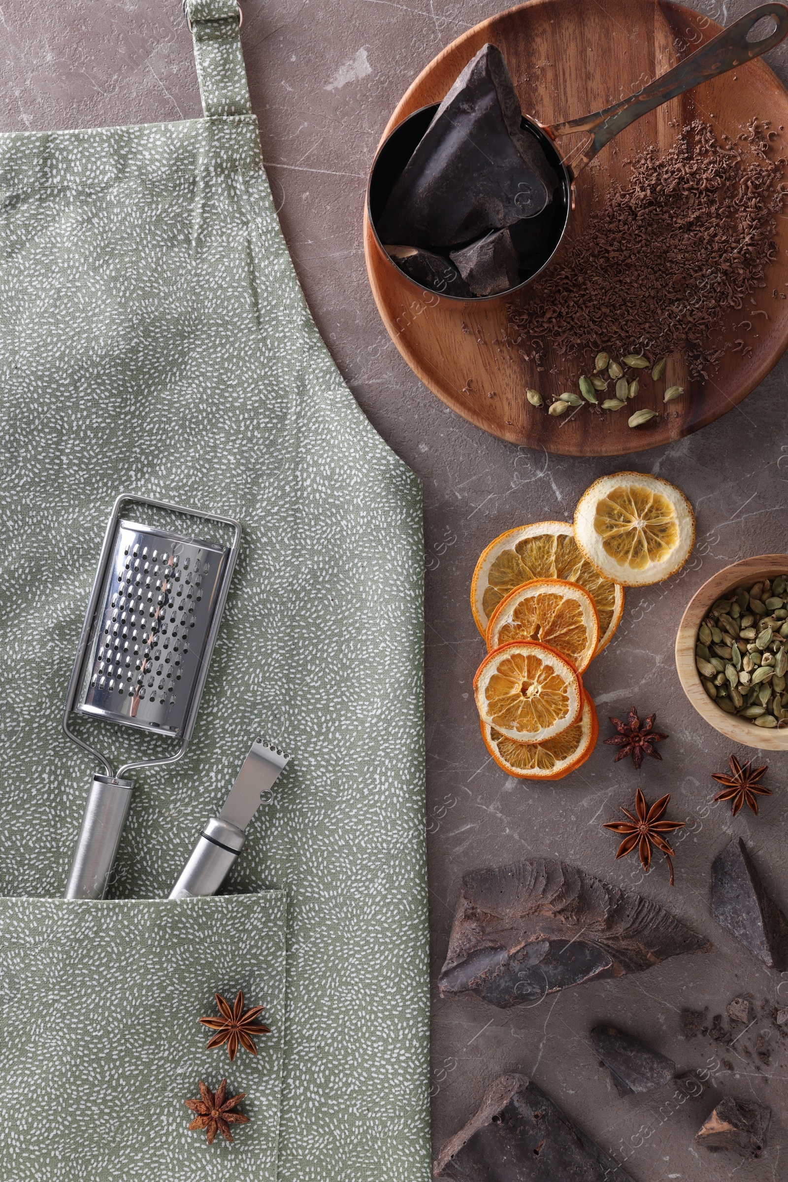 Photo of Clean apron with kitchen tools and different ingredients on brown marble table, flat lay