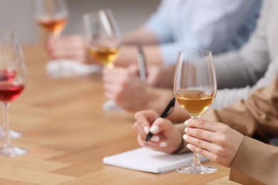 Photo of Sommeliers tasting different sorts of wine at table indoors, closeup