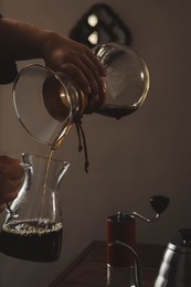 Photo of Barista pouring coffee into glass jug in cafe, closeup