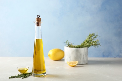 Photo of Composition with rosemary oil in bottle and bowl on light table