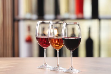 Photo of Different sorts of wine in glasses on table indoors