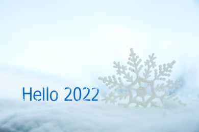 Hello 2022. Beautiful decorative snowflake in white snow 