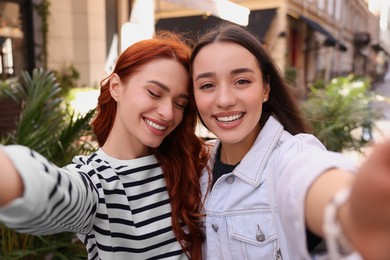 Photo of Happy friends taking selfie outdoors on autumn day