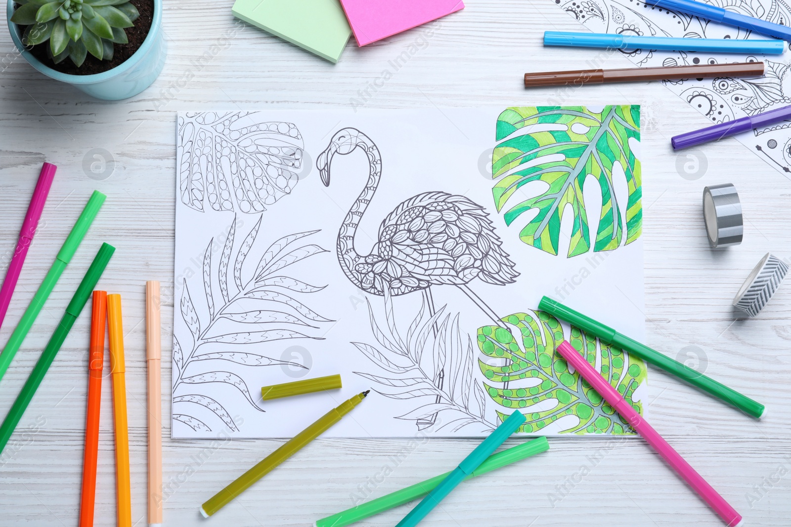 Photo of Antistress coloring page and felt tip pens on white wooden table, flat lay