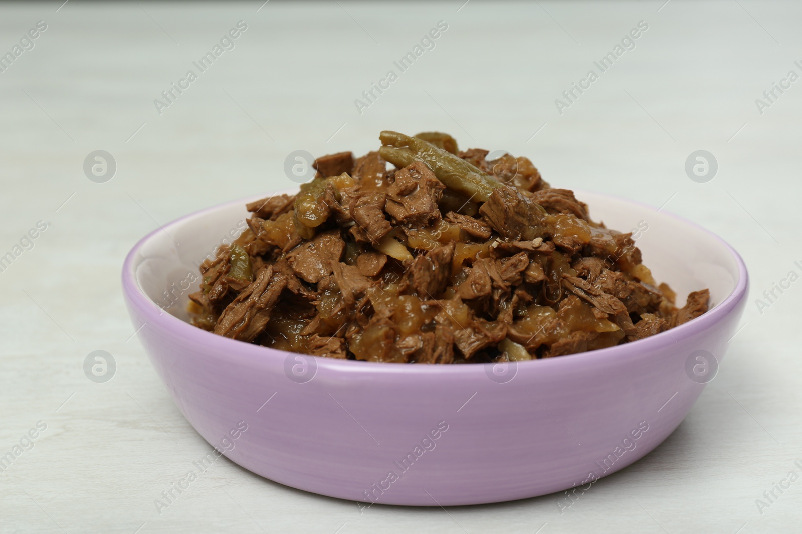 Photo of Wet pet food in feeding bowl on white table