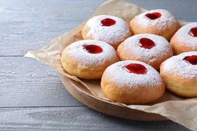 Photo of Hanukkah doughnuts with jelly and sugar powder on grey wooden table, closeup