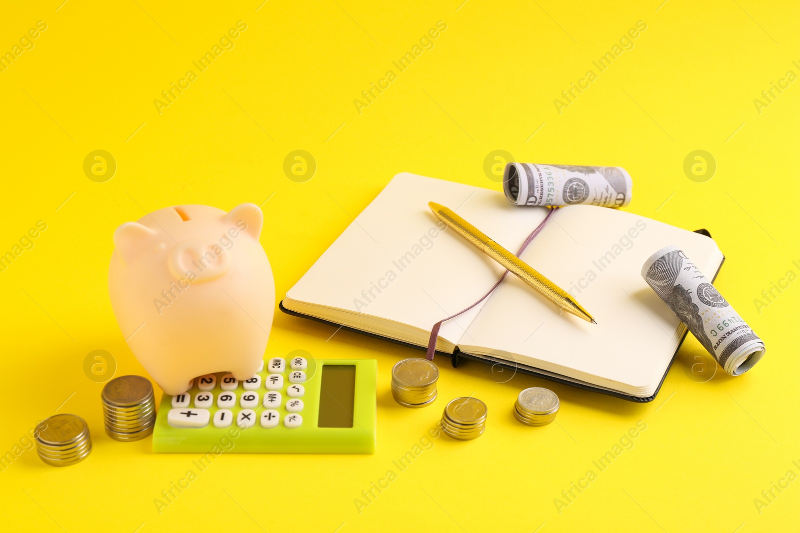 Photo of Financial savings. Piggy bank, money, calculator and stationery on yellow background