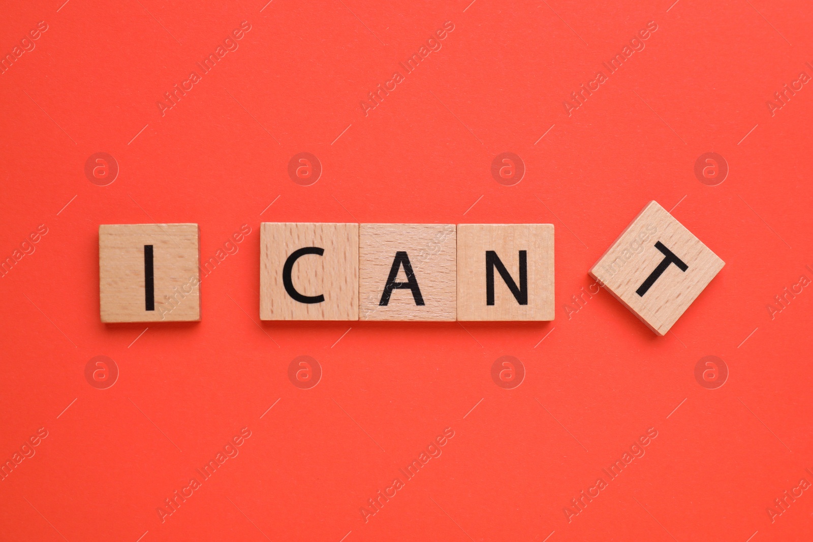 Photo of Motivation concept. Changing phrase from I Can't into I Can by removing square with letter T on red background, top view