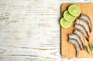 Photo of Fresh raw shrimps with rosemary and lime on white wooden table, top view. Space for text