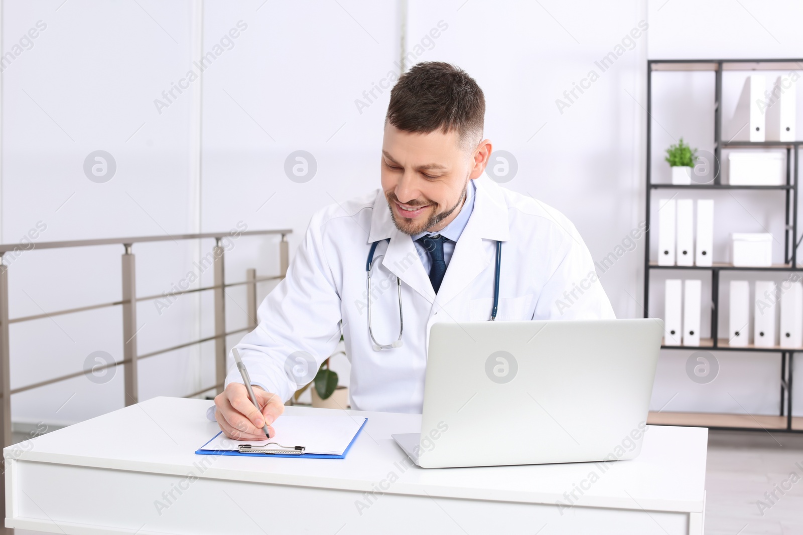 Photo of Pediatrician working on laptop at desk in office