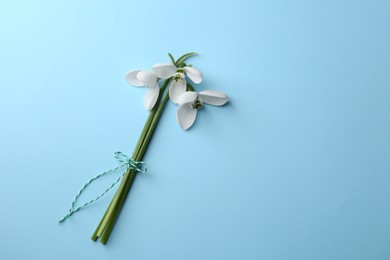 Beautiful snowdrops on light blue background, flat lay. Space for text