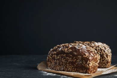 Photo of Fresh wholegrain bread on table against black background. Space for text
