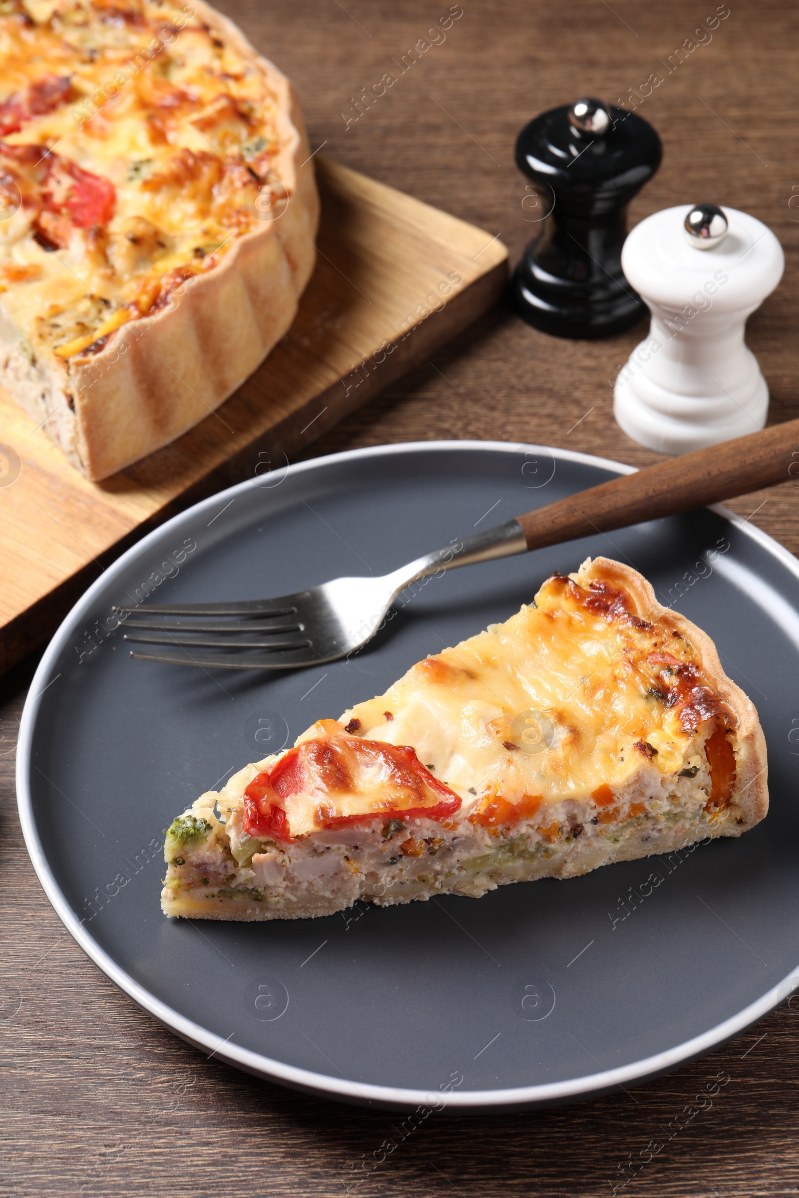 Photo of Tasty quiche with chicken, vegetables and cheese served on wooden table