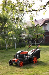 Modern lawn mower on green grass in garden