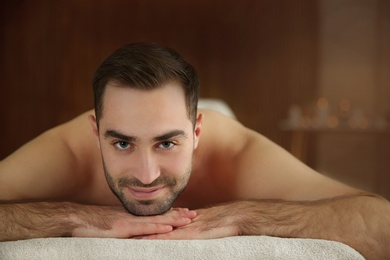 Photo of Handsome man relaxing on massage table in spa salon