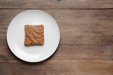 Photo of Toast with tasty nut butter on wooden table, top view. Space for text