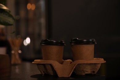 Takeaway coffee cups with cardboard holder on wooden table indoors