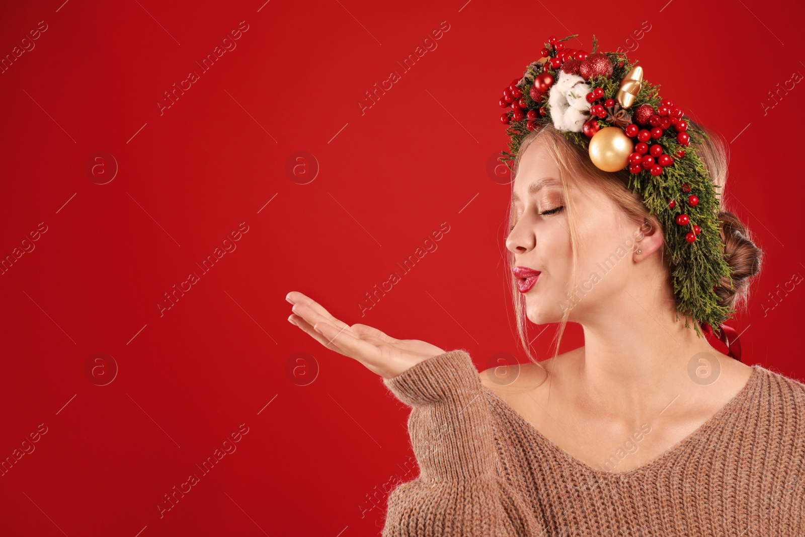 Photo of Beautiful young woman wearing Christmas wreath on red background. Space for text