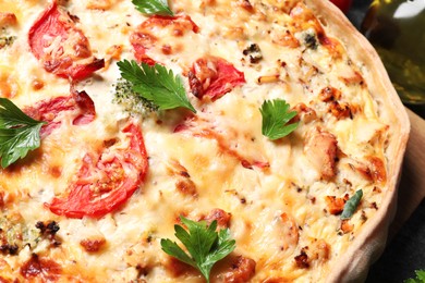 Photo of Tasty quiche with tomatoes, parsley and cheese on table, closeup