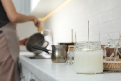 Photo of Homemade candle and blurred view of woman on background