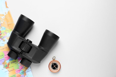 Photo of Modern binoculars, compass and world map on white background, flat lay. space for text