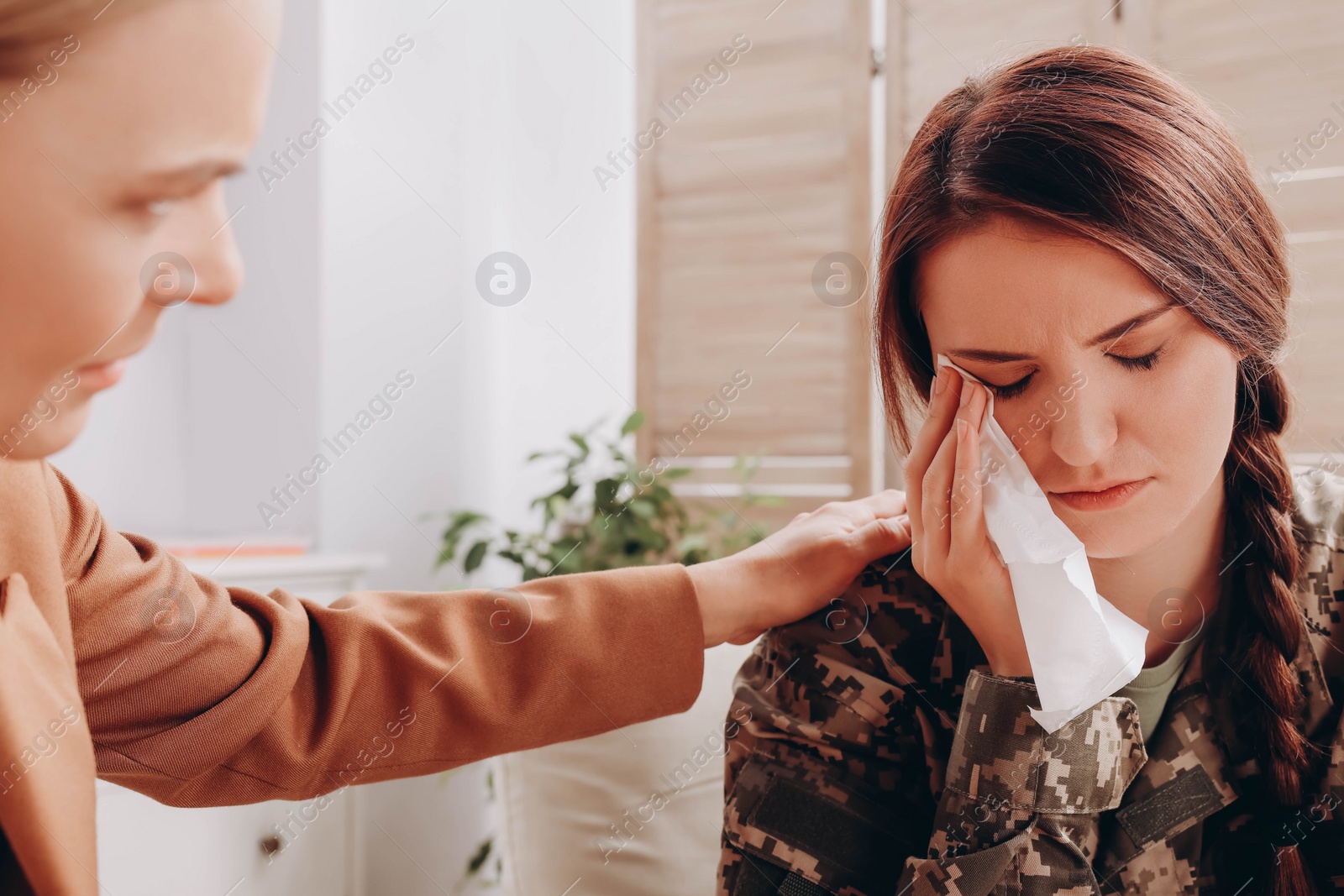 Photo of Psychologist supporting sad female military officer indoors