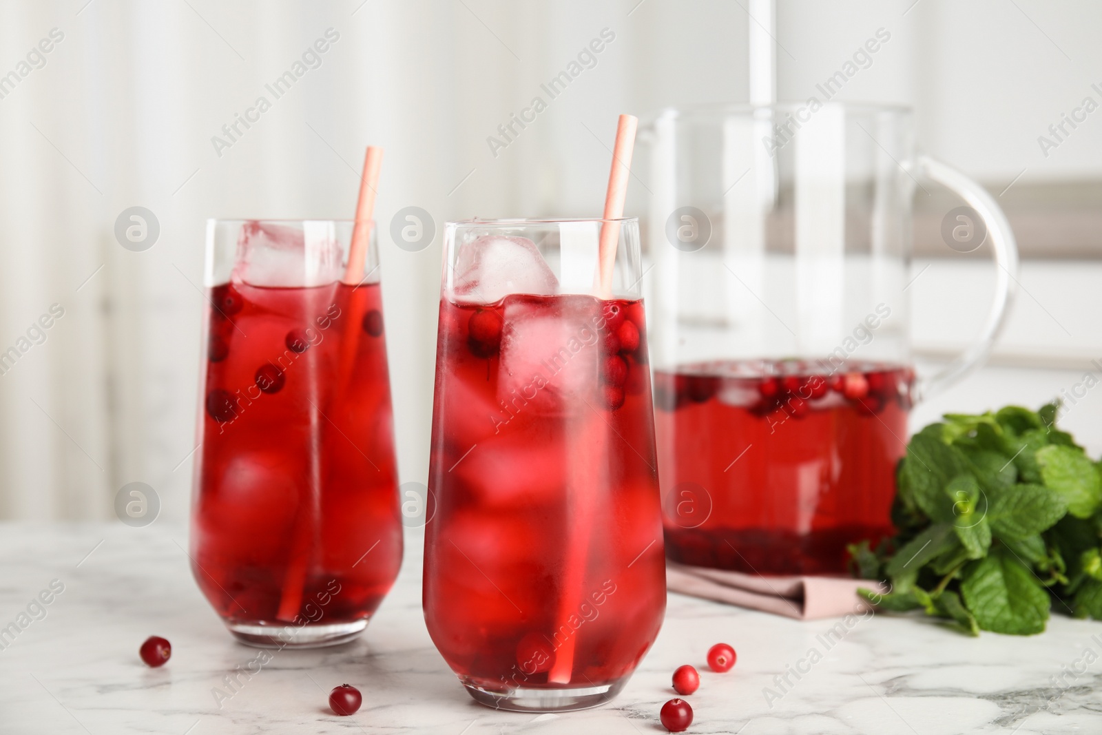 Photo of Tasty refreshing cranberry cocktail on white marble table indoors