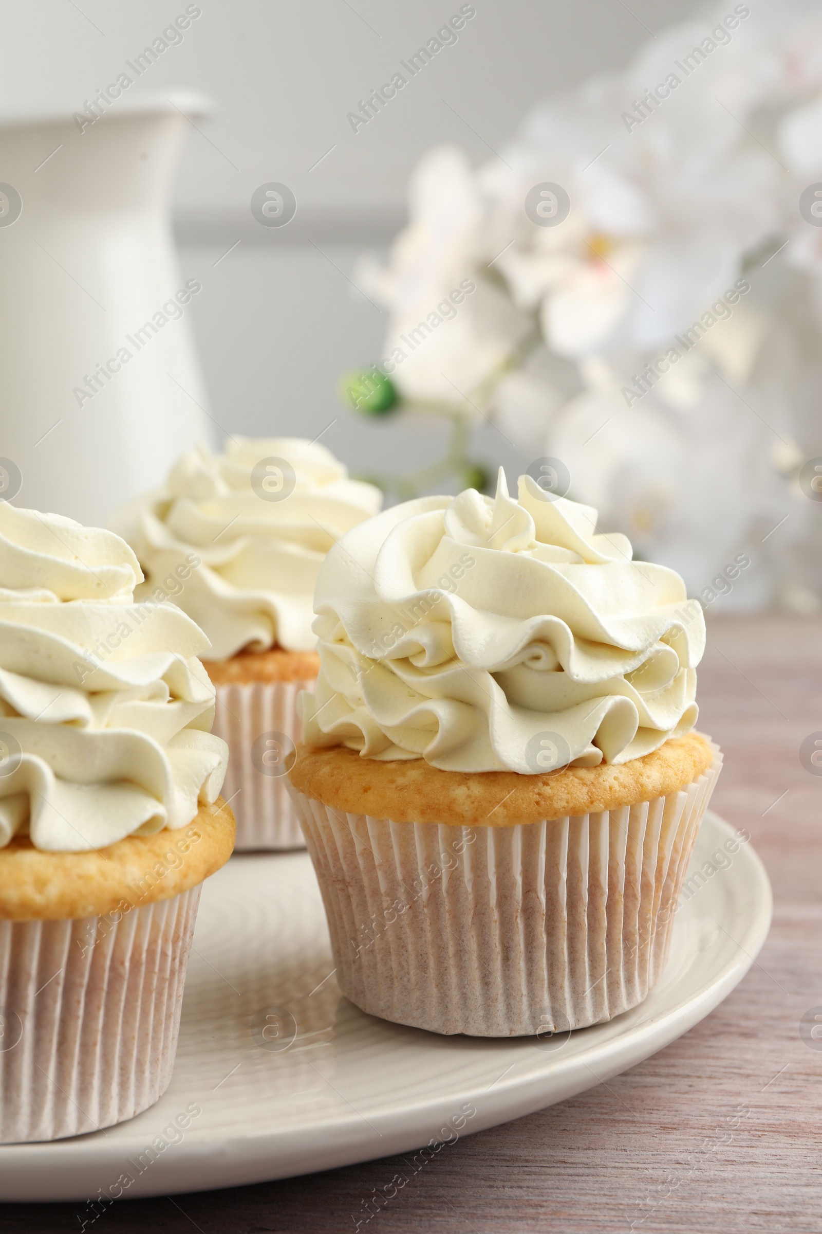 Photo of Tasty cupcakes with vanilla cream on pink wooden table, closeup