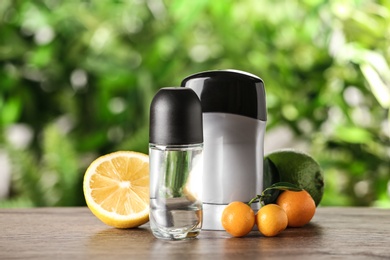 Photo of Different deodorants and citrus fruits on wooden table against blurred background