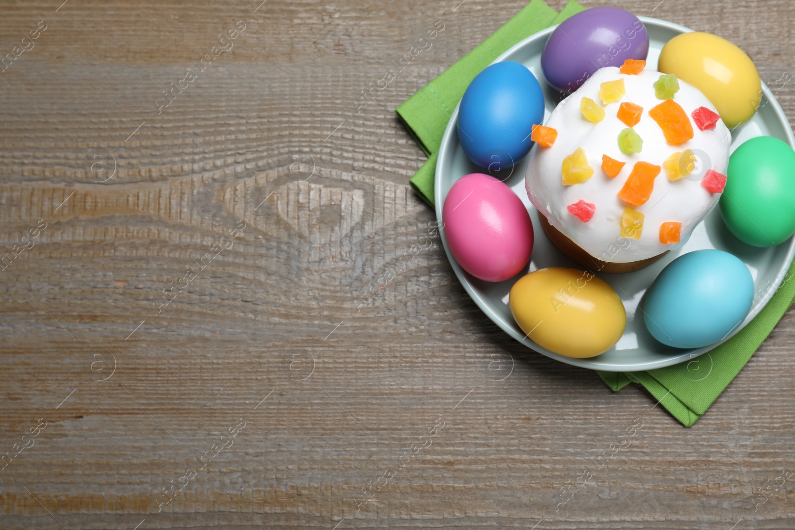 Photo of Traditional decorated Easter cake and colorful eggs on wooden table, top view. Space for text