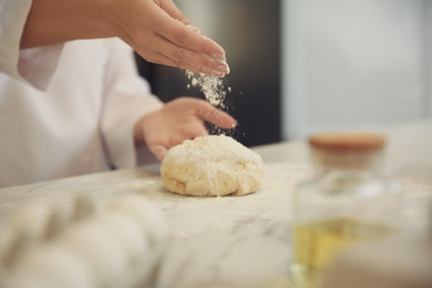 Photo of Chef cooking dough at table in kitchen, closeup