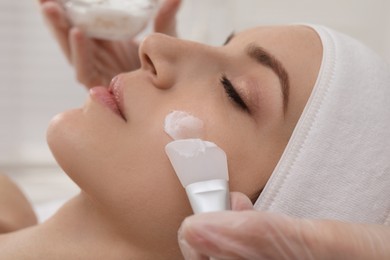 Young woman during face peeling procedure in salon, closeup