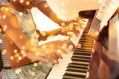 Image of Christmas and New Year music. Woman with little girl to play piano indoors. Bokeh effect