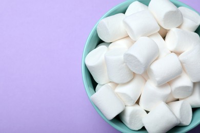 Delicious puffy marshmallows on lilac background, top view. Space for text