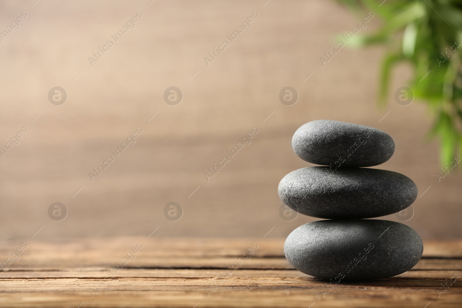 Photo of Stack of spa stones on wooden table. Space for text