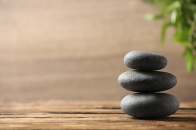 Photo of Stack of spa stones on wooden table. Space for text